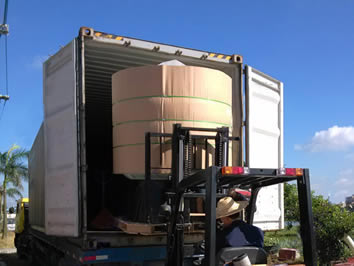 A red trailer is putting a well packed FRP tank in a truck.